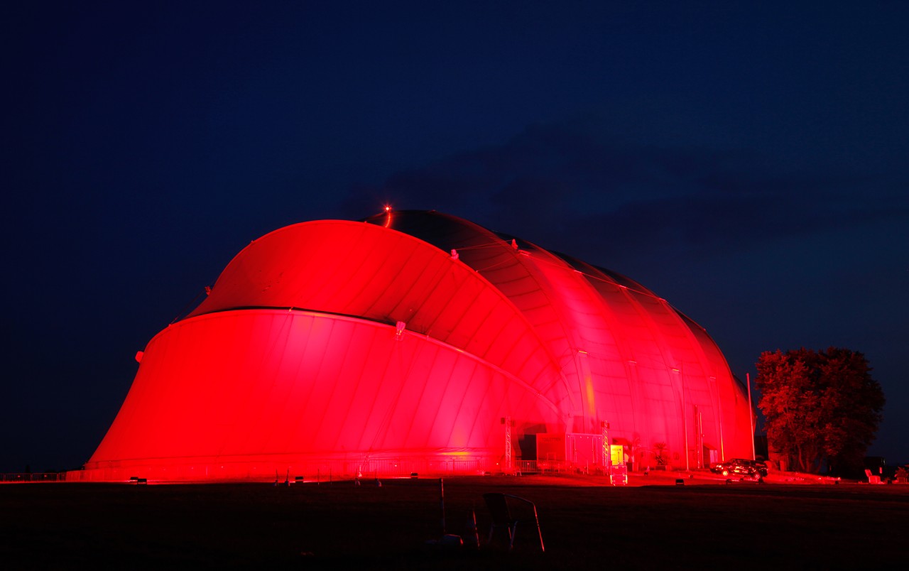 Die Luftschiffhalle in Mülheim: Hier im Juni 2020, als sie im Rahmen der Aktion„Night of Light“ mit rotem Licht angestrahlt wurde, um die Politik auf die drohende Pleitewelle von Kultureinrichtungen durch die Corona-Pandemie aufmerksam zu machen.