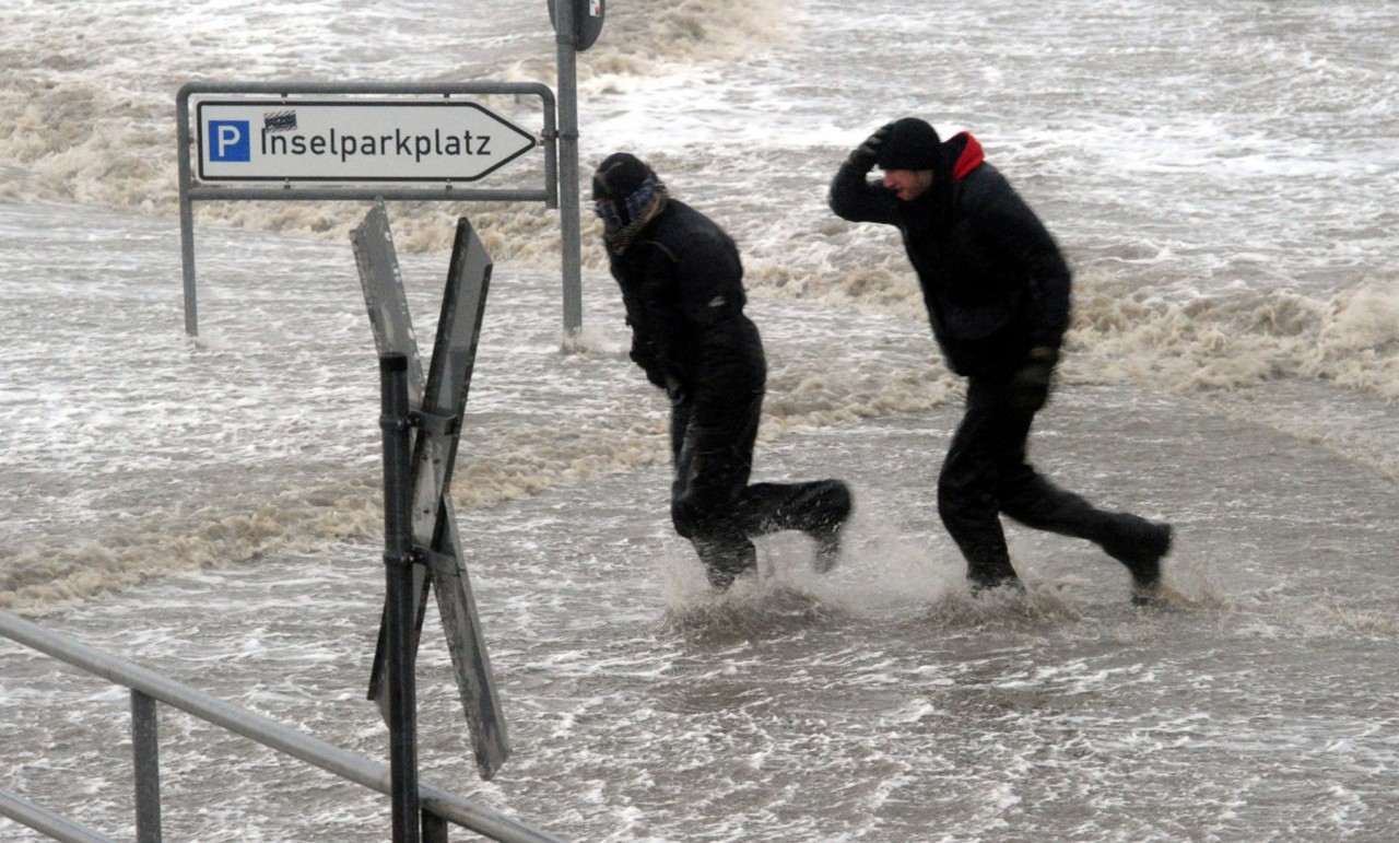 Passanten laufen am 05.12.2013 über den überfluteten Fähranleger in Dagebüll an der Nordsee in Schleswig-Holstein. Das Orkantief "Xaver" hat den Norden mit voller Wucht erreicht.