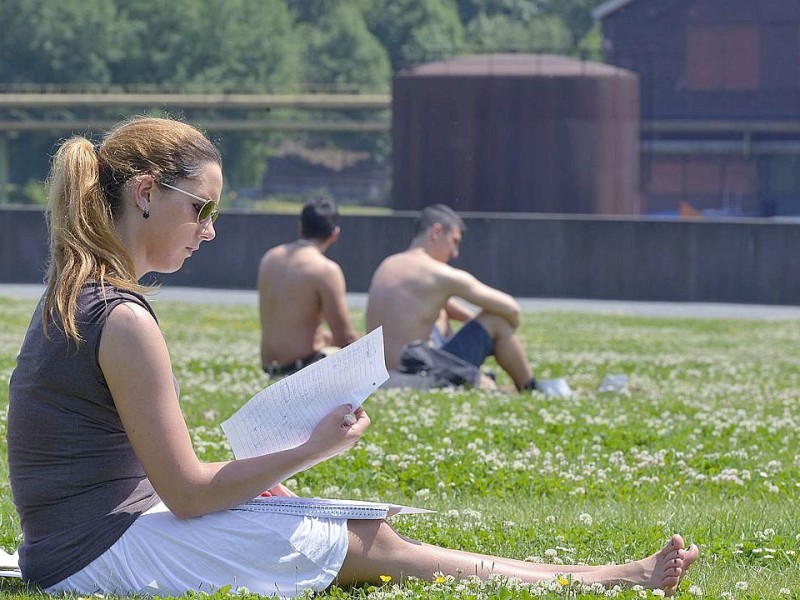 Die Lektüre wird nach draußen verlegt. Diese Frau nutzt das Sommerwetter zum Lesen im Westpark vor der Jahrhunderthalle in Bochum.