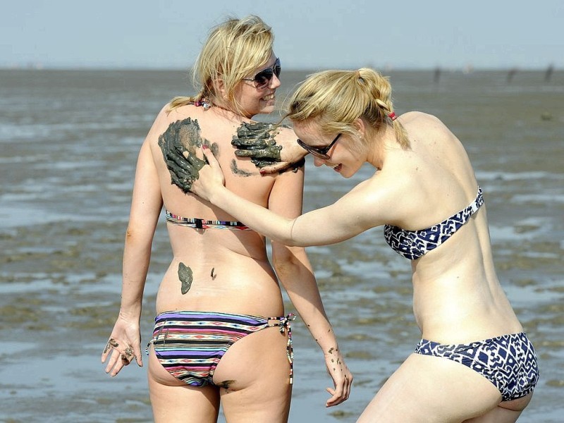 Schlammkur gegen die warmen Luftströme aus Afrika: Zwei Bremerinnen nutzen den Schlamm im Watt vor dem Strand von Cuxhaven-Duhnen zur Abkühlung.