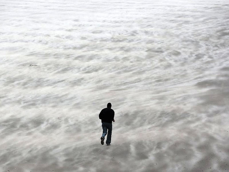 Dieses Bild zeigt einen Mann am Strand von Blankenberge, Belgien. Vor dem Hafen von...