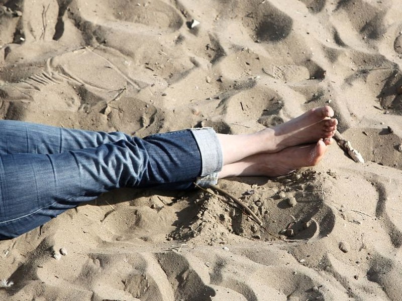 Eine Frau liegt im Sand an der Elbe in Hamburg. In der Hansestadt erreichte die Temperatur...