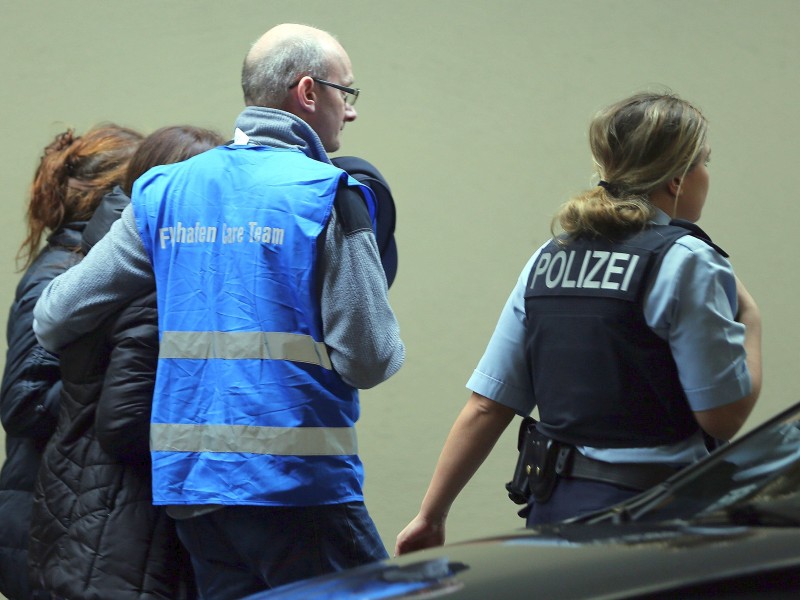 Ein Mitarbeiter des Flughafen Care Team läuft am 24. März am Flughafen Düsseldorf begleitet von Polizisten mit Angehörigen von Insassen des abgestürzten Airbus.