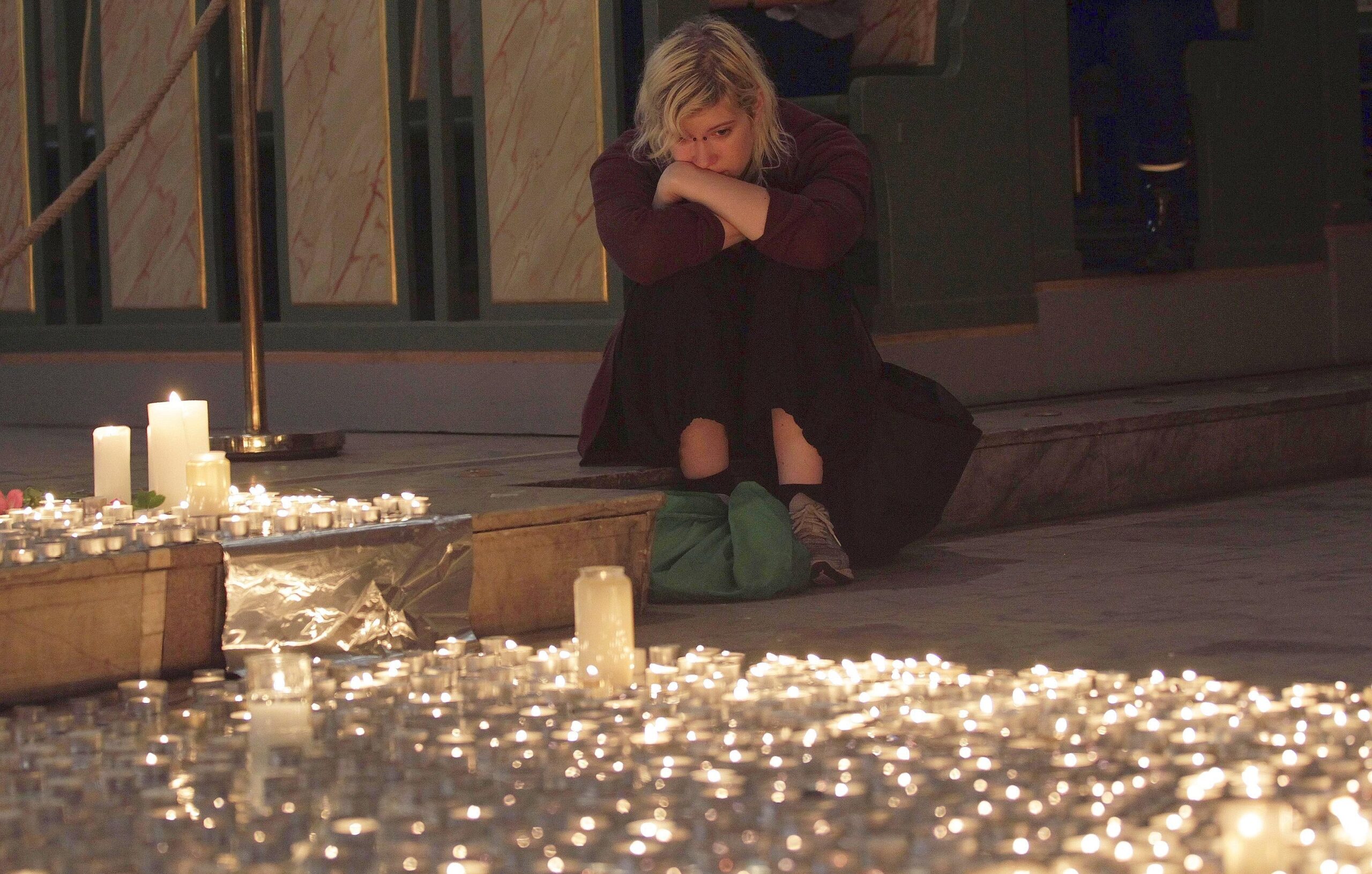Eine junge Frau sitzt in sich gekehrt auf dem Boden der Kathedrale in Oslo.
