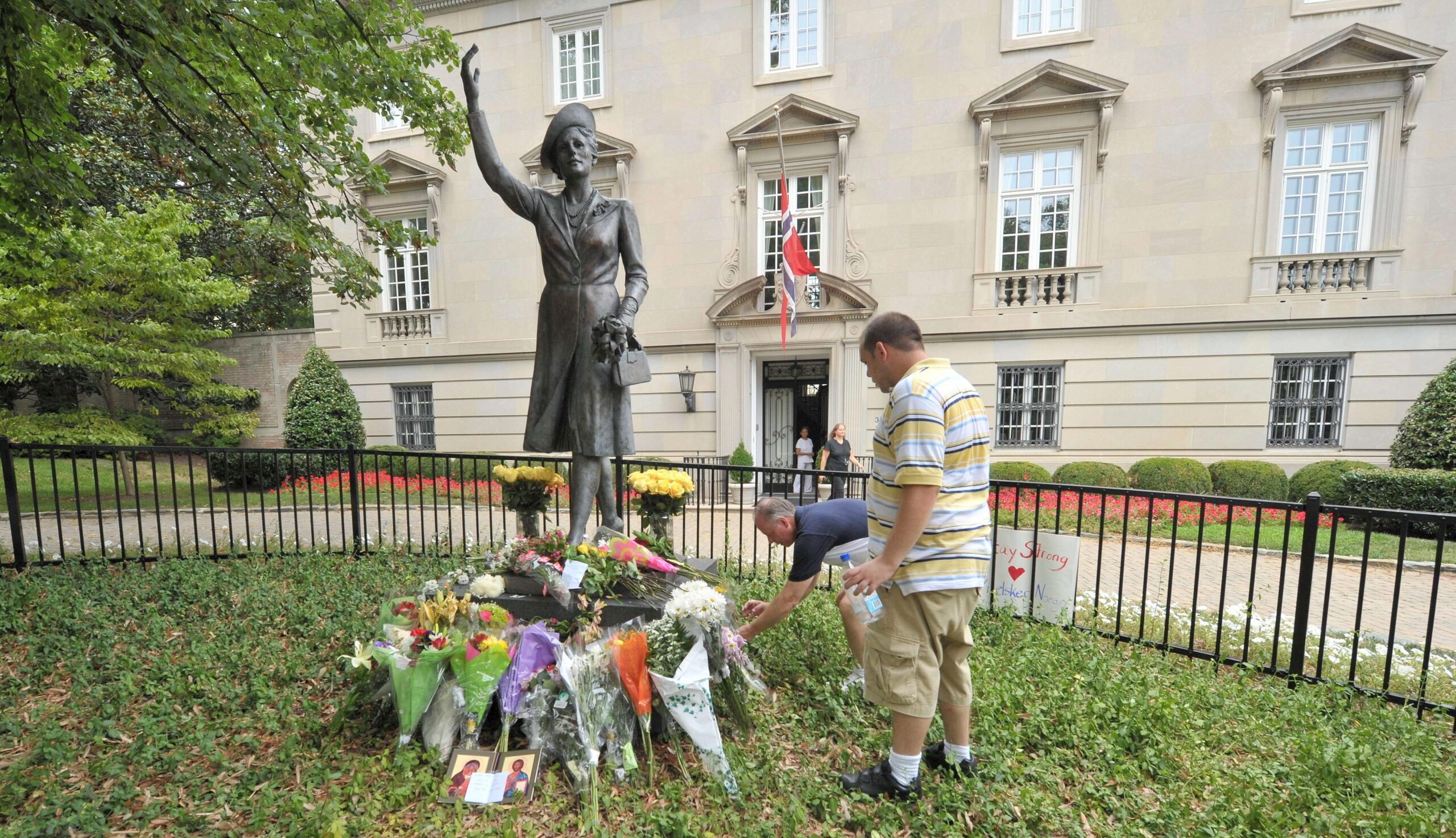 Zwei Männer legen in Washington Blumen am Fuße der Statue von Norwegens Kronprinzessin Martha nieder.