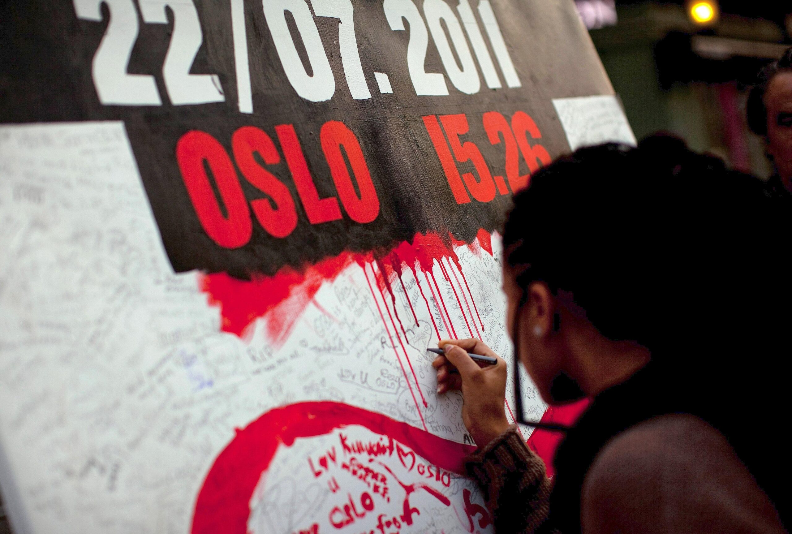 Ein Mädchen malt ein Herz an eine Gedenkmauer in Oslo. Das Attentat löste weltweit Entsetzen aus.