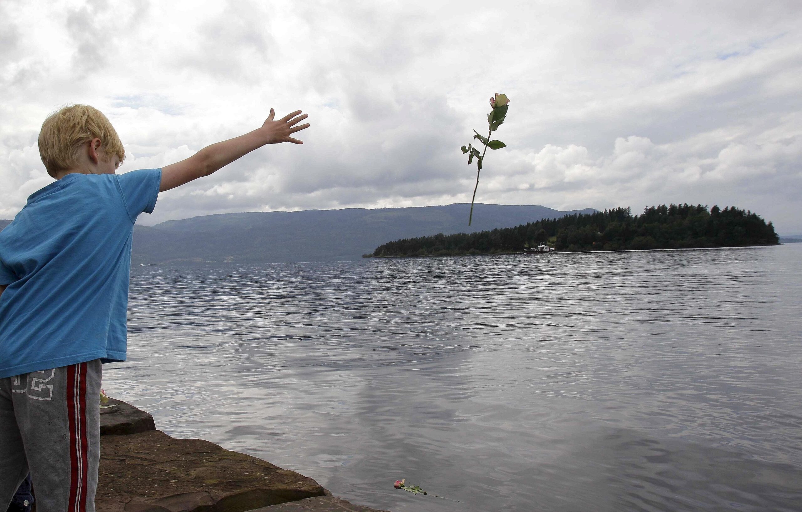 Ein Junge wirft eine rote Rosen in den See gegenüber der Insel Utöya. Wie werden die Anschläge Norwegens Gesellschaft verändern?