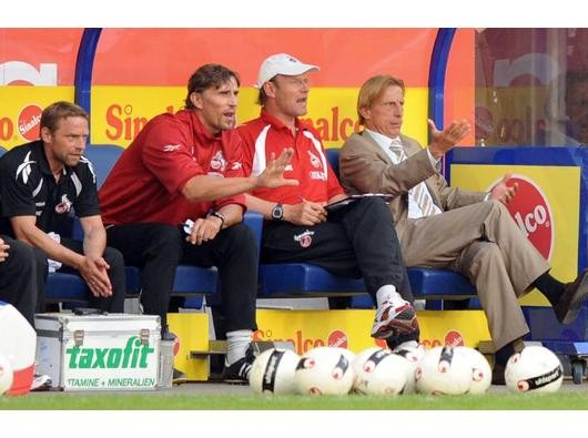 Hier sieht man ihn auf der Bank mit Trainer Christoph Daum, Co-Trainer Roland Koch und Techniktrainer Thomas Häßler.