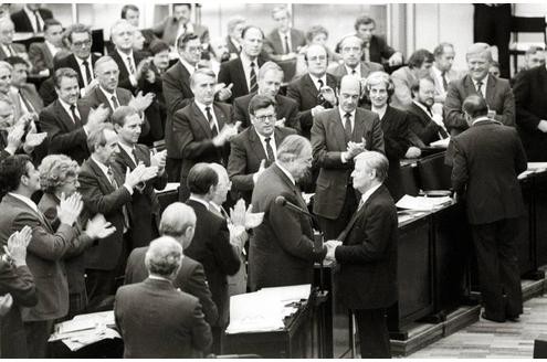 Das Misstrauensvotum kostet Bundeskanzler Helmut Schmidt (SPD) am 1. Oktober 1982 sein Amt. Schmidt gratuliert seinem Nachfolger Helmut Kohl (CDU) unter dem Applaus der Bundestagsabgeordneten zum Gewinn der Abstimmung im Bundestag.