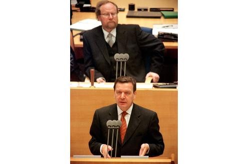 Gerhard Schröder verliest seine Regierungserklärung, während Bundestagspräsident Wolfgang Thierse (SPD) ernst auf ihn herabblickt.