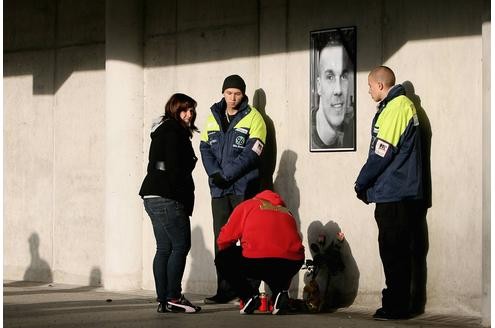 Eine Trauerende entzündet an einer Mahnwache am Stadion eine Kerze für Robert Enke.