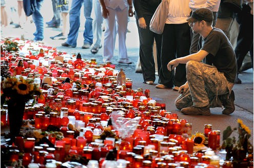 Zahlreiche Menschen legen am Ort der Loveparade-Tragödie Blumen und Kränze an der Wand nieder, an der die Opfer starben.