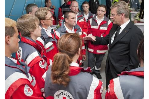 Bundespräsident Christian Wulff (rechts) spricht am 31. Juli auch mit Helfern des Deutschen Roten Kreuzes, die bei der Katastrophe enormen physischen als auch psychischen Belastungen ausgesetzt waren.