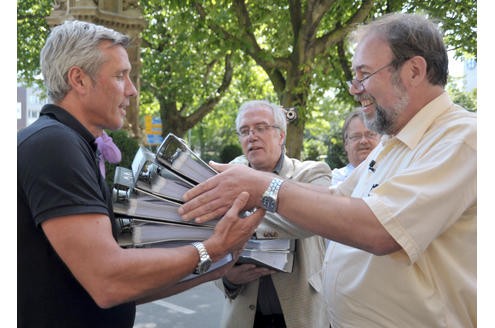 Einen Tag später übergeben Werner Hüsken (rechts) und Peter Heß (Mitte) an Peter Greulich von der Stadt (links) Listen mit 10.000 Unterschriften der Duisburger Bürger mit der Rücktrittsforderung an OB Sauerland.