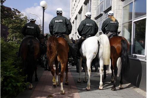 Berittene Polizisten reiten am Samstag vor dem Hauptbahnhof in Dortmund linksgerichteten Demonstranten hinterher. 