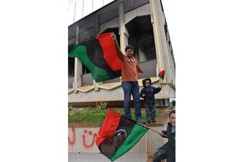 Jungen mit der Flagge der Aufständischen vor der Ruine des Gaddafi-Palastes auf dem Katiba-Gelände