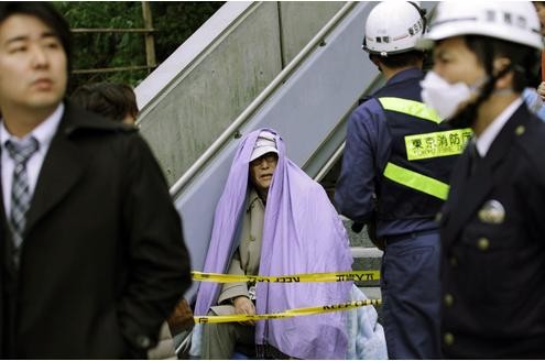 ...ein in eine Decke gehüllter Mann läuft verängstigt durch die Straße, nachdem er aus einem Gebäude in Tokio evakuiert worden war...