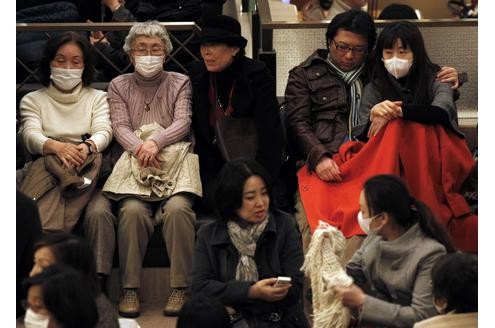 Gestrandete Japaner warten in einer Hotellobby darauf, dass die öffentlichen Verkehrsmittel wieder funktionieren.