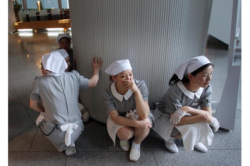 Die Zimmermädchen eines Hotels in Tokio ducken sich während des Erdbebens.