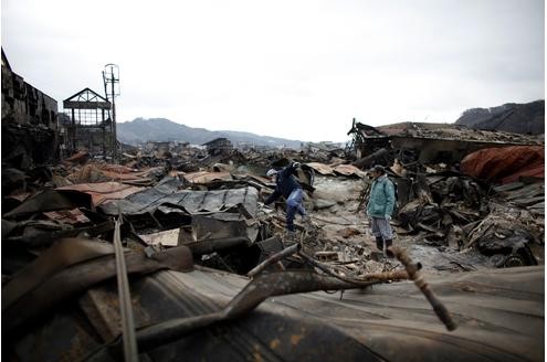Überlebende in den Trümmern von Otsuchi, das durch das Erdbeben und den Tsunami zerstört wurde. 12.000 der 15.000 Bewohner werden vermisst.