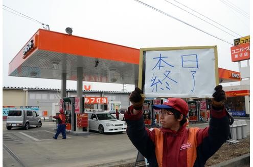 A petrol station employee raises an 