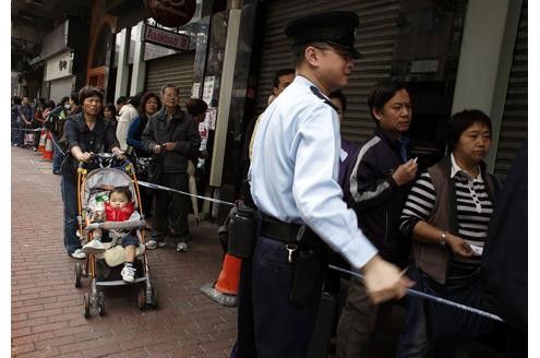 Dienstag morgen in Hong Kong: Ein Polizist vor einem Laden, der japanisches Milchpulver verkauft. Hunderte von Menschen haben die Sorge, dass künftig produziertes Milchpulver von dort radioaktiv verstrahlt sein könnte.