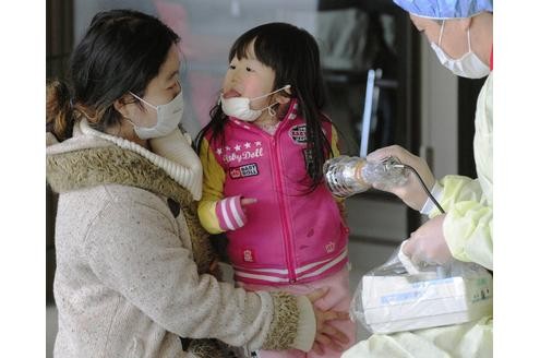 Mutter und Tochter werden gescannt in einer Turnhalle bei Fukushima.