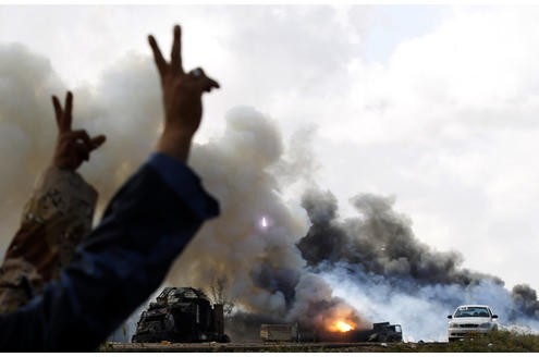 Gaddafi-Gegner machen das Siegeszeichen, nachdem alliierte Kräfte Panzer der Gaddafi-Truppen zerstört haben.