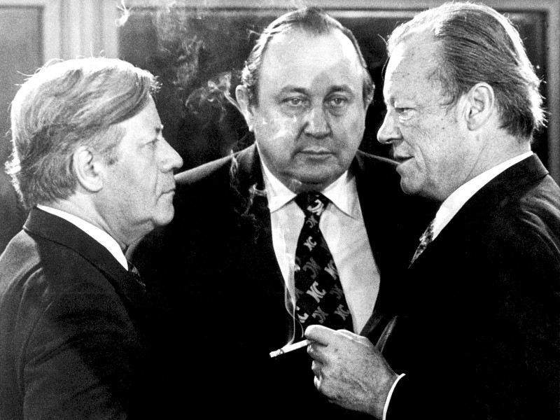 Stationen aus dem Leben eines Staatsmanns: Vor Beginn der Sitzung im Bonner Bundeskanzleramt am 13. Dezember 1976 unterhalten sich Bundeskanzler Helmut Schmidt (SPD, l.), Genscher (FDP) und der SPD-Vorsitzende Willy Brandt (r.). 