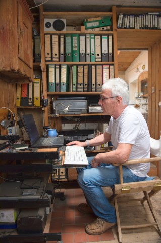 Günther Hamker sitzt in seinem Waldhäuschen an seinem Laptop. 
