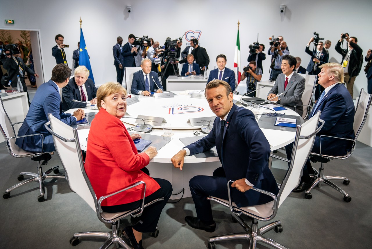 Angela Merkel im Kreis von Trump, Johnson und Sarkozy: Während die Männer alle in blau-grauen Anzügen zum G7-Gipfel kamen, fällt Kanzlerin Merkel mit einem knalligen roten Blazer auf.