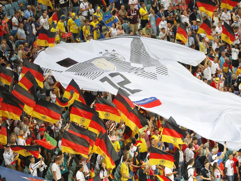 Im Stadion in Sotschi feiern die Deutschland-Anhänger mit schwarz-rot-goldenen Fahnen und einem riesigen Trikot.