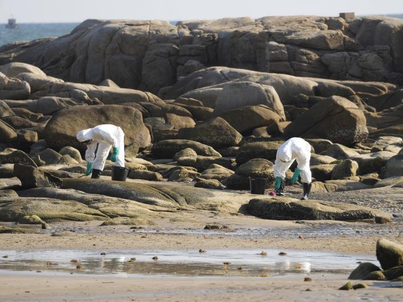 Arbeiter schrubben Öl von den Felsen am Strand von Mae Ramphueng, nachdem eine Ölpipeline vor der Küste der Provinz Rayong im Osten Thailands ausgelaufen war.