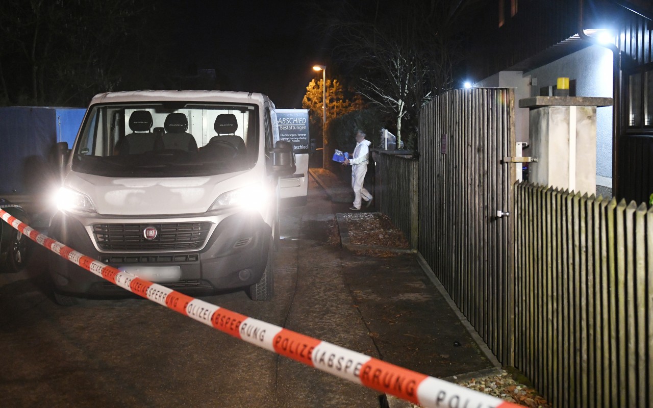 Ein Polizist bringt Beweise aus dem Haus in Bayern, in dem drei Leichen gefunden worden.