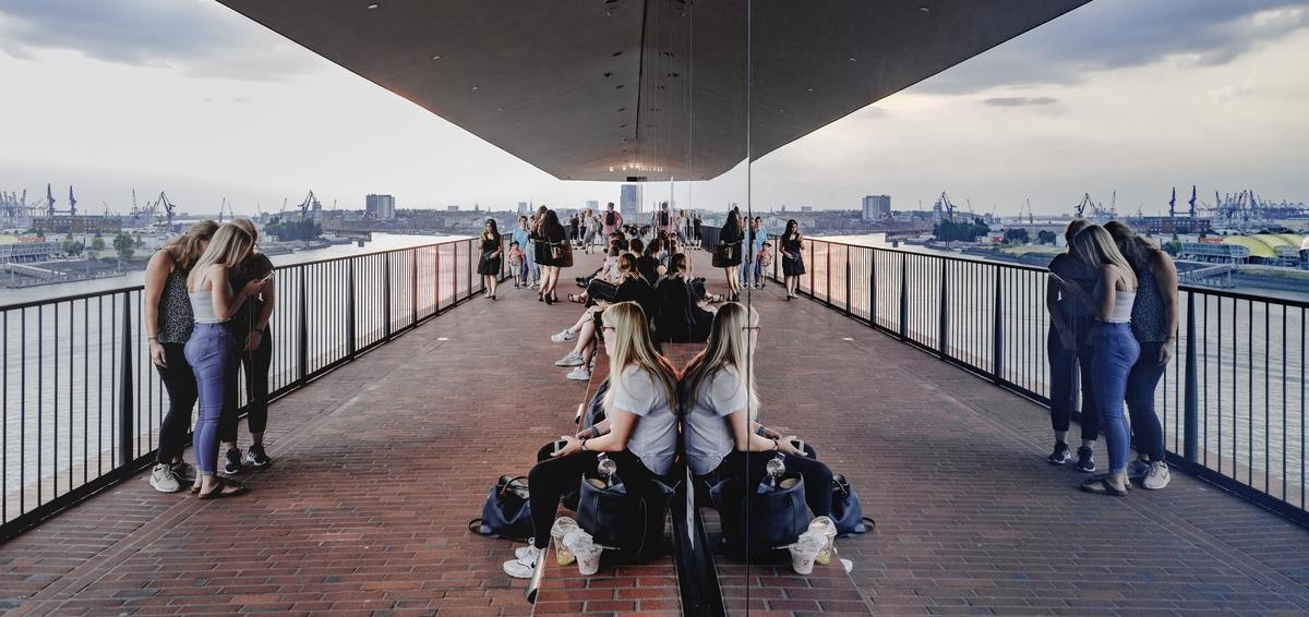 Besucher der Plaza der Elbphilharmonie spiegeln sich in den Fenstern des Konzerthauses. In 37 Meter Höhe über der Elbe bietet die Plaza der Elbphilharmonie einen tollen Blick über den Hafen und die Stadt Hamburg. 