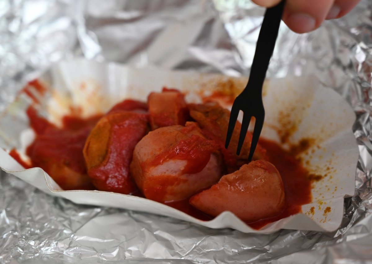 Eine Currywurst mit Pommes in einer Schale.