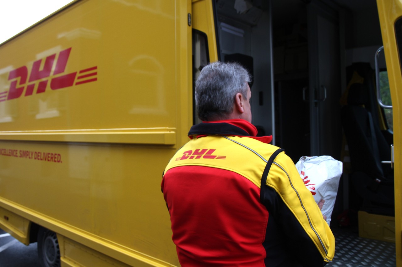 Immer Sachte: Ein DHL-Paketbote lädt eine Sendung in seinem Fahrzeug ab. 