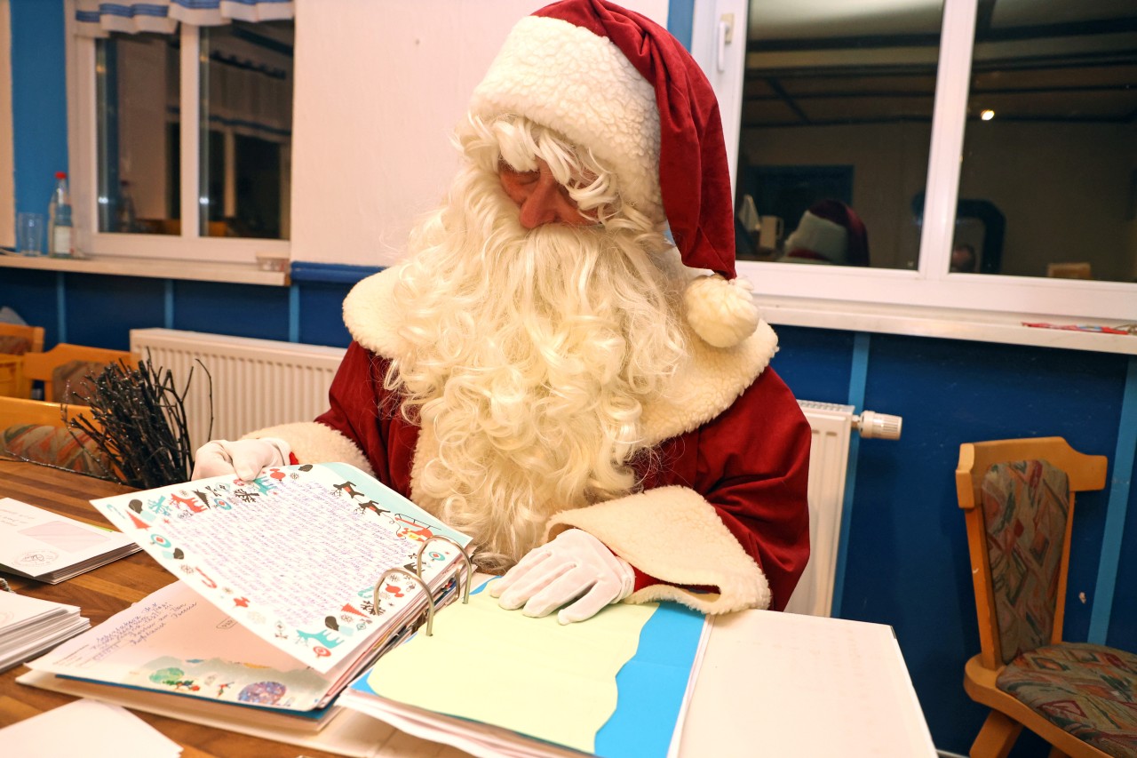 Deutsche Post: Eine als Weihnachtsmann verkleidete Frau liest Briefe, die Kinder geschrieben haben.