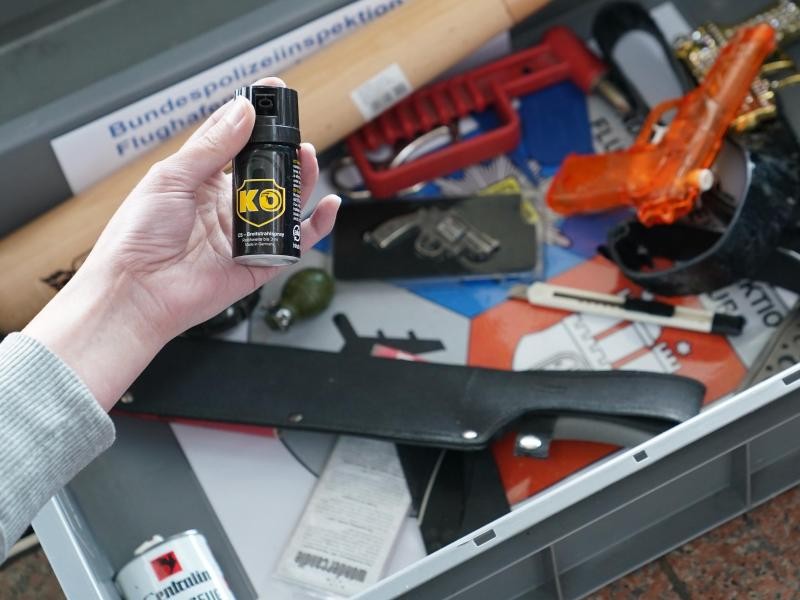 Eine Bundespolizisten hält eine konfiszierte Pfefferspray-Dose hoch. Waffen und waffenähnliche Gegenstände dürfen nicht im Handgepäck transportieret werden.