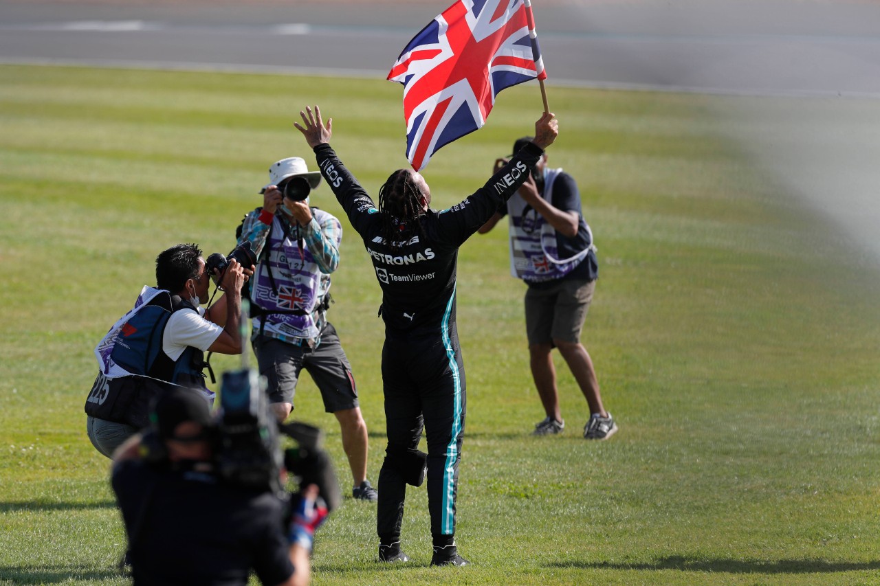 Lewis Hamilton jubelt mit Flagge.