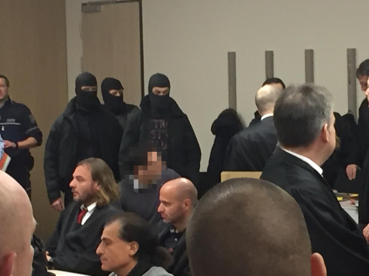 Personenschützer begleiten einen der Angeklagten in den Gerichtssaal.