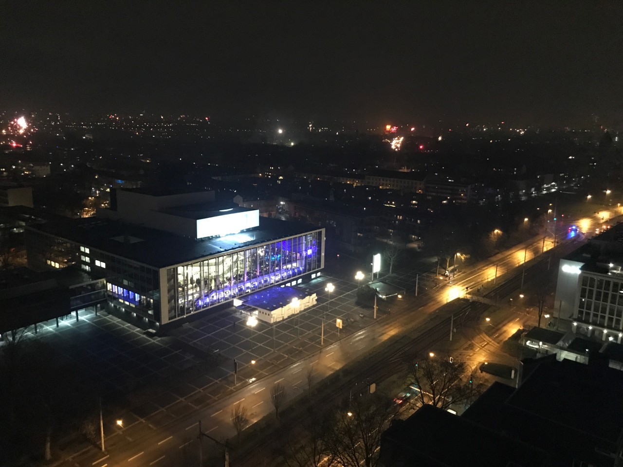 Ein Blick auf das Musiktheater im Revier aus dem „Weißen Riesen“ Gelsenkirchen. Im Hintergrund leuchten Silvesterraketen.