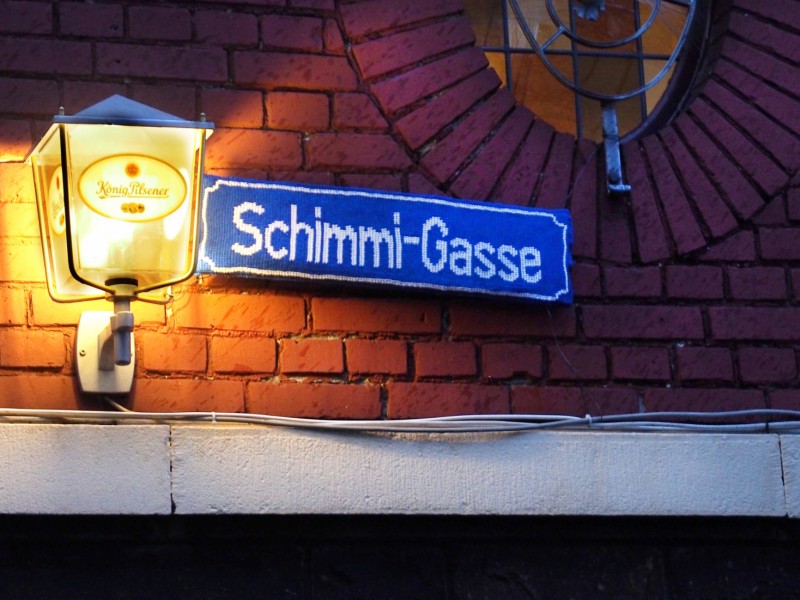 Ein gehäkeltes Straßen-Schild: die Schimmi-Gasse in Ruhrort