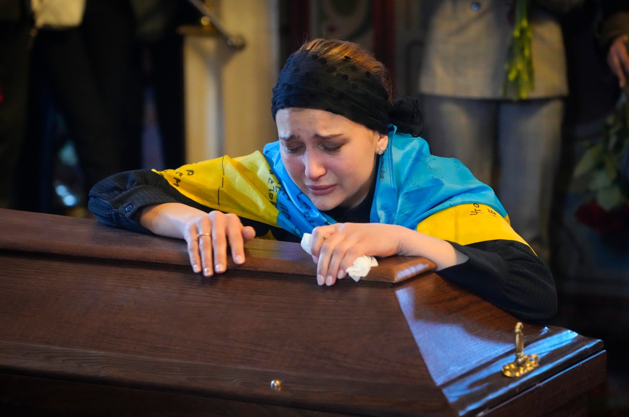 Die Freundin des verstorbenen Ukraine-Journalisten weint an seinem Sarg.