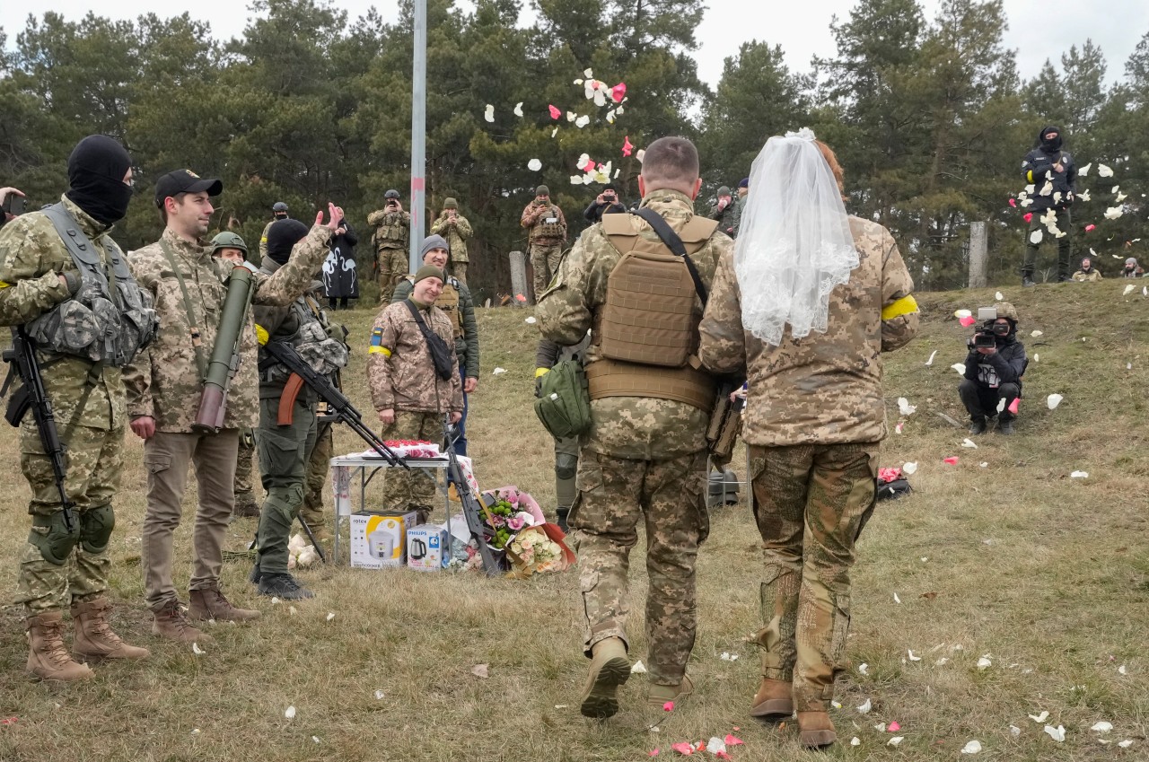 Soldaten werfen Rosenblätter über die frisch verheirateten Mitglieder der ukrainischen Territorialen Verteidigungskräfte Lesia Iwashchenko und Walerii Fylymonow während ihrer Hochzeitszeremonie an einem Kontrollpunkt in der ukrainischen Hauptstadt.