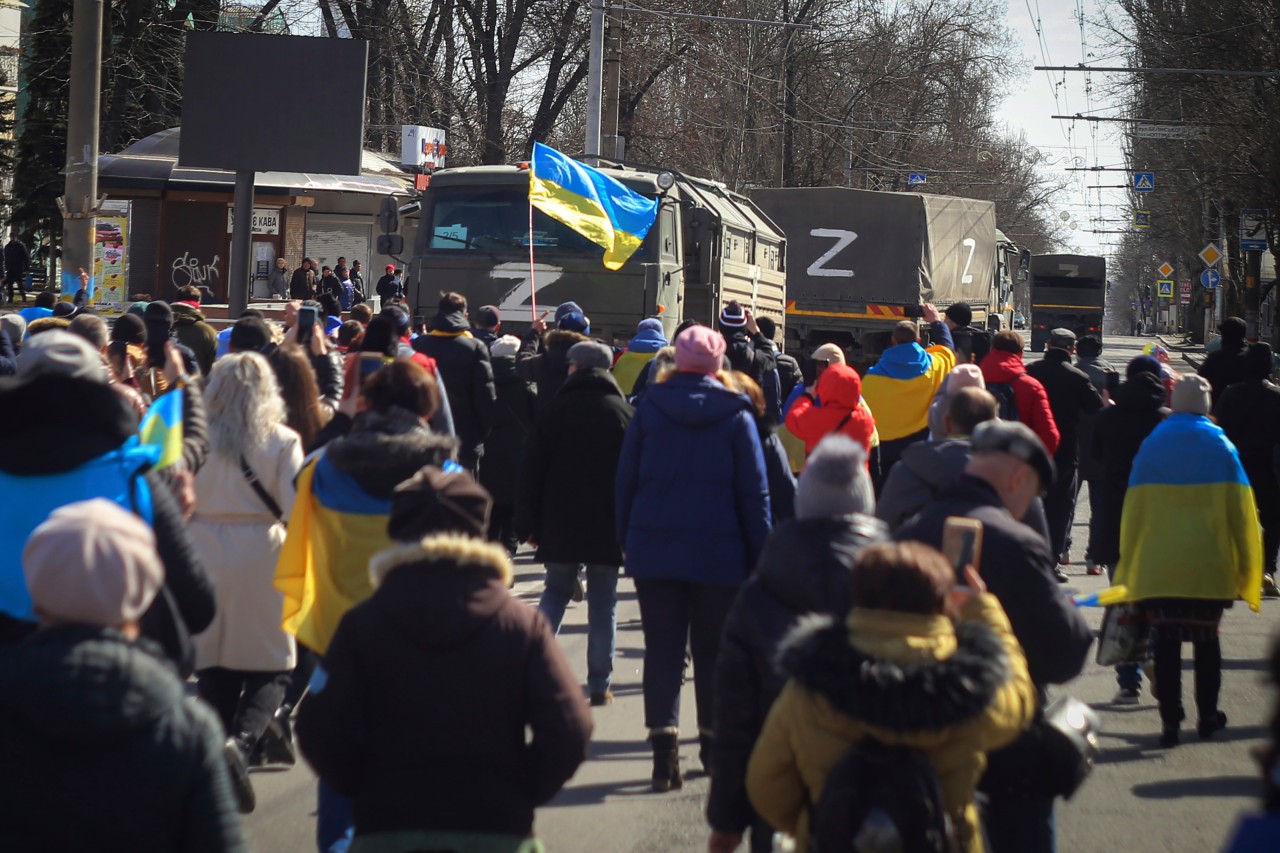 Ukraine: Menschen mit ukrainischen Fahnen gehen während einer Kundgebung gegen die russische Besatzung in Cherson im März 2022 auf Lastwagen der russischen Streitkräfte zu.