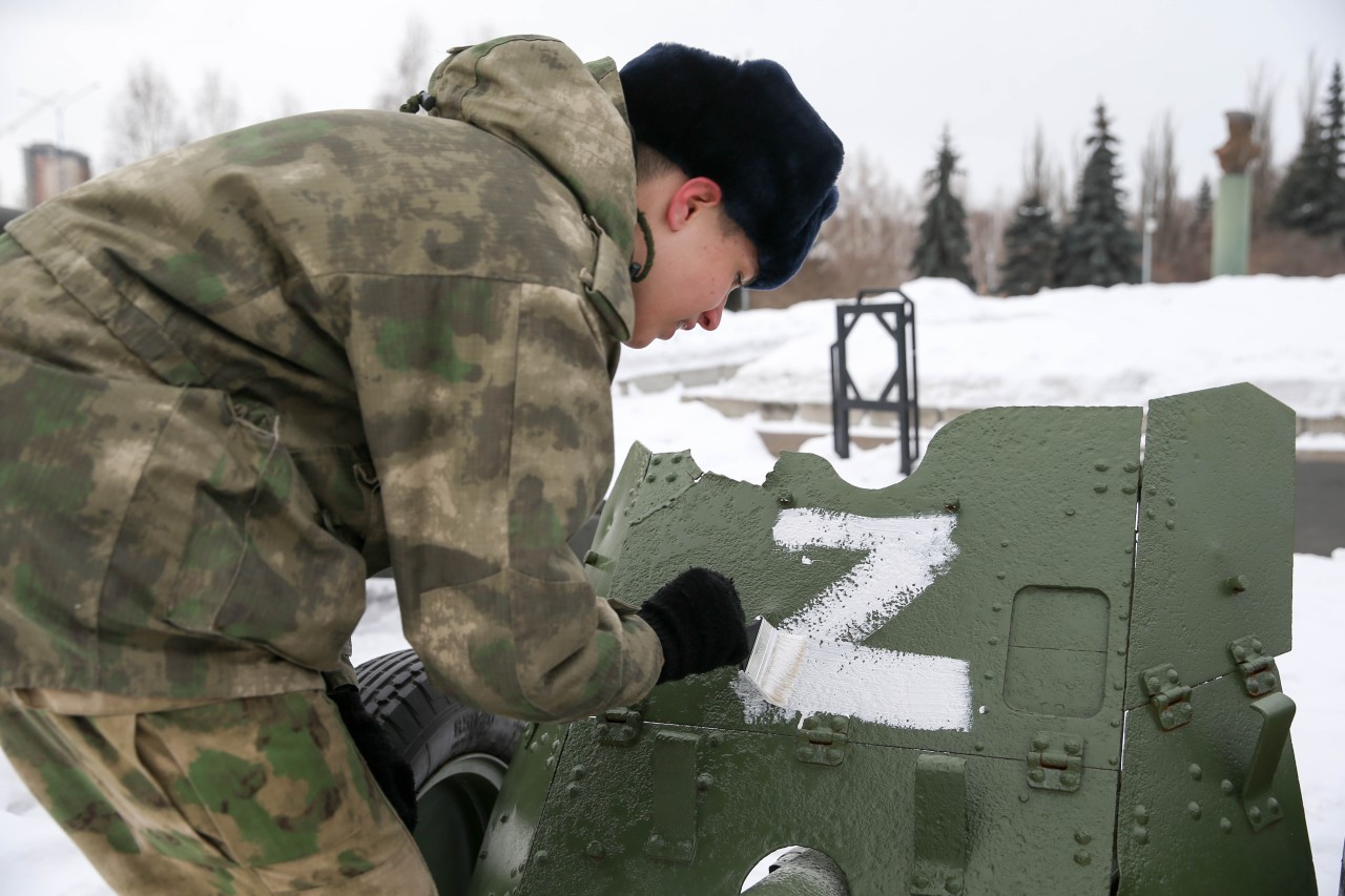 Ein Soldat malt ein Z auf ein Militärfahrzeug. 