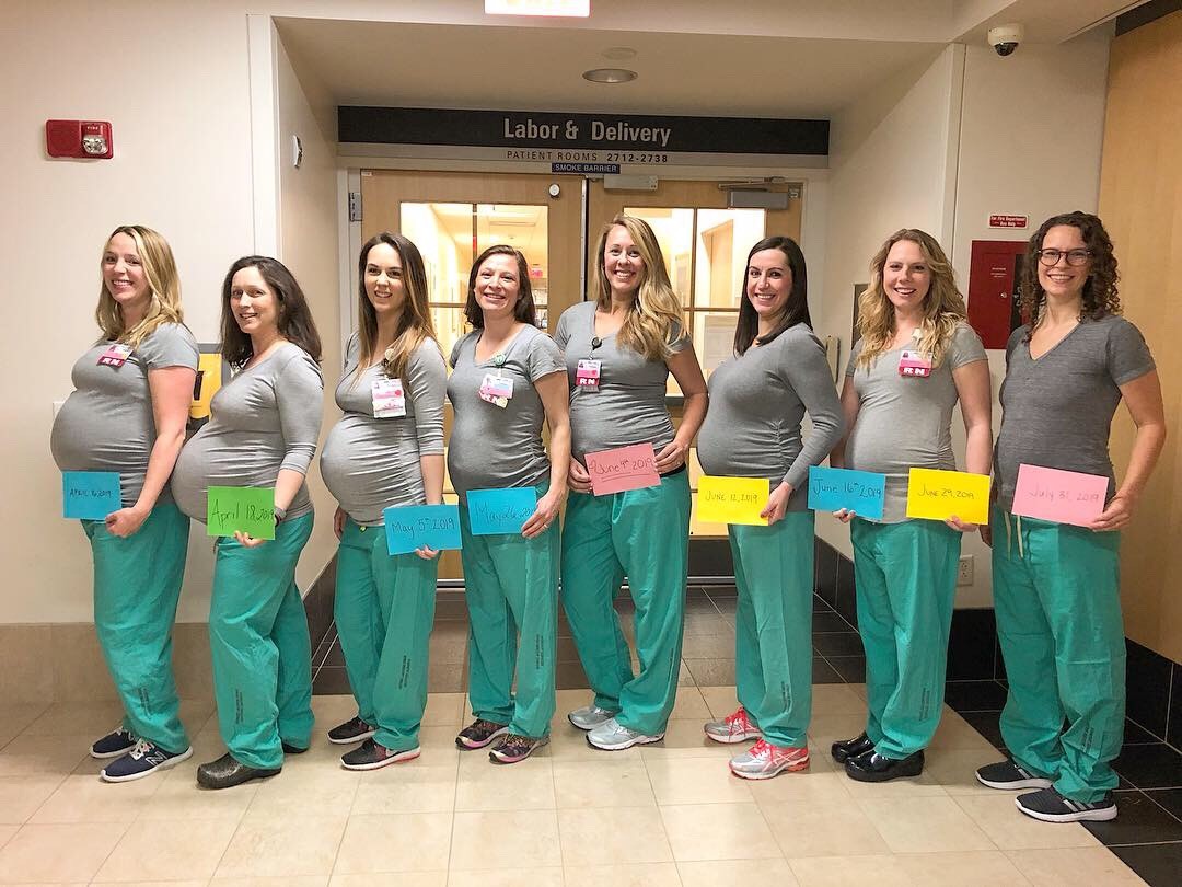 Die schwangeren Krankenschwestern mit Schildern ihrer ausgerechneten Geburtstermine – eine hält zwei Schilder für die fehlende Kollegin.