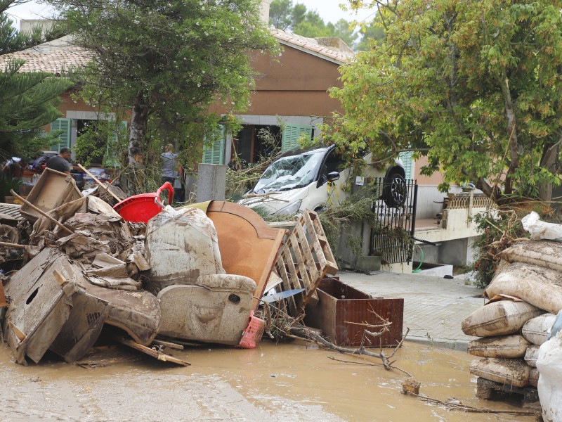 In der Stadt Sant Llorenç des Cardassar, die das Unwetter am stärksten traf, zeigte sich den Menschen ein Bild der Verwüstung: Ein Autowrack und Trümmer liegen nach einem schweren Unwetter an einem Haus.