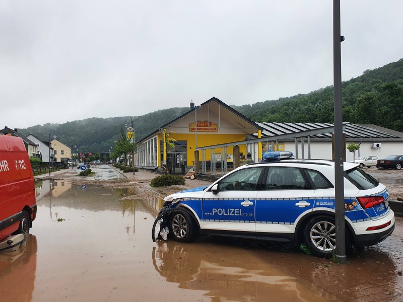 Auch ein Polizeifahrzeug wurde Opfer der Flutkatastrophe und steht nun verlassen auf der überschwemmten Straße.